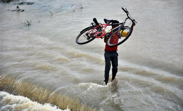 man carrying cycle in floods in pune